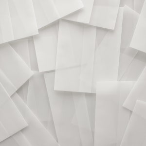 May include: A stack of white envelopes, overlapping and creating a textured background.
