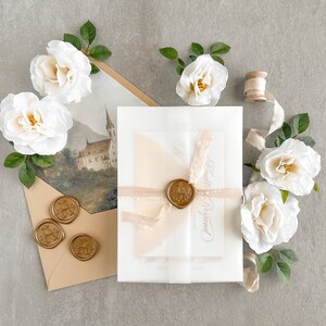 May include: A white envelope with a wax seal and a pink ribbon. The envelope is on a light gray surface with white roses and a spool of ribbon.