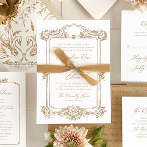 May include: Gold foil wedding invitation suite with a swan design. The invitation features a gold foil border with ornate details and the text "Mr. and Mrs. Charles Ludwig request the pleasure of your company at the marriage of their daughter Caroline Rose". The RSVP card features the text "Happily Accepts - Sally Dulines".