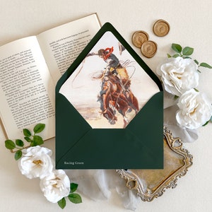 Op de afbeelding: Een donkergroene envelop met de tekst Racing Green op de voorflap. De envelop is geopend en toont een illustratie van een cowboy op een bokkend bruin paard die een lasso vasthoudt. De envelop is omringd door witte rozen.