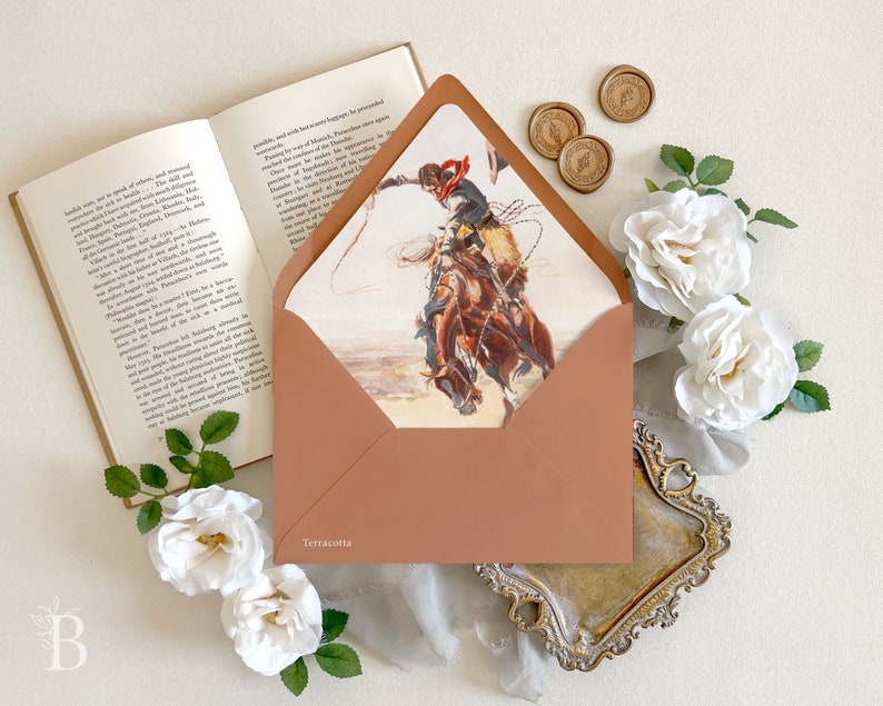 Op de afbeelding: Een terracotta-kleurige envelop met een bedrukte voering met een illustratie van een persoon op een paard die een lasso zwaait. Het woord Terracotta staat in het wit gedrukt op de linkerbenedenhoek van de voorste envelopflap.