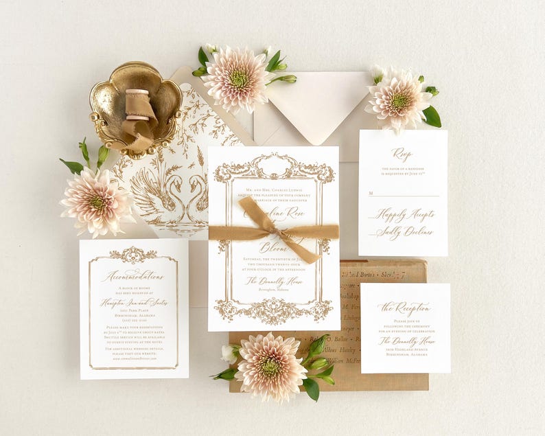 May include: Wedding invitation suite with a gold and white color scheme. The invitation features a decorative frame with a swan design. The RSVP card includes the text "Happily Accept" and the reception card includes the text "The Reception".