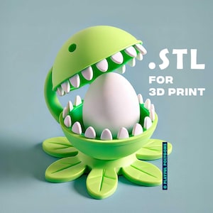 May include: A green 3D printed plant with a large open mouth, holding a white egg. The plant has a base with six leaves. The text .STL FOR 3D PRINT is visible in the image.