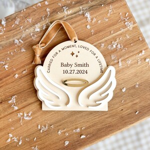 Wood or frosted acrylic baby memorial ornament.  Features matte white acrylic wings and a gold halo.  Personalize with baby's name and date.  Includes khaki velvet ribbon for hanging.