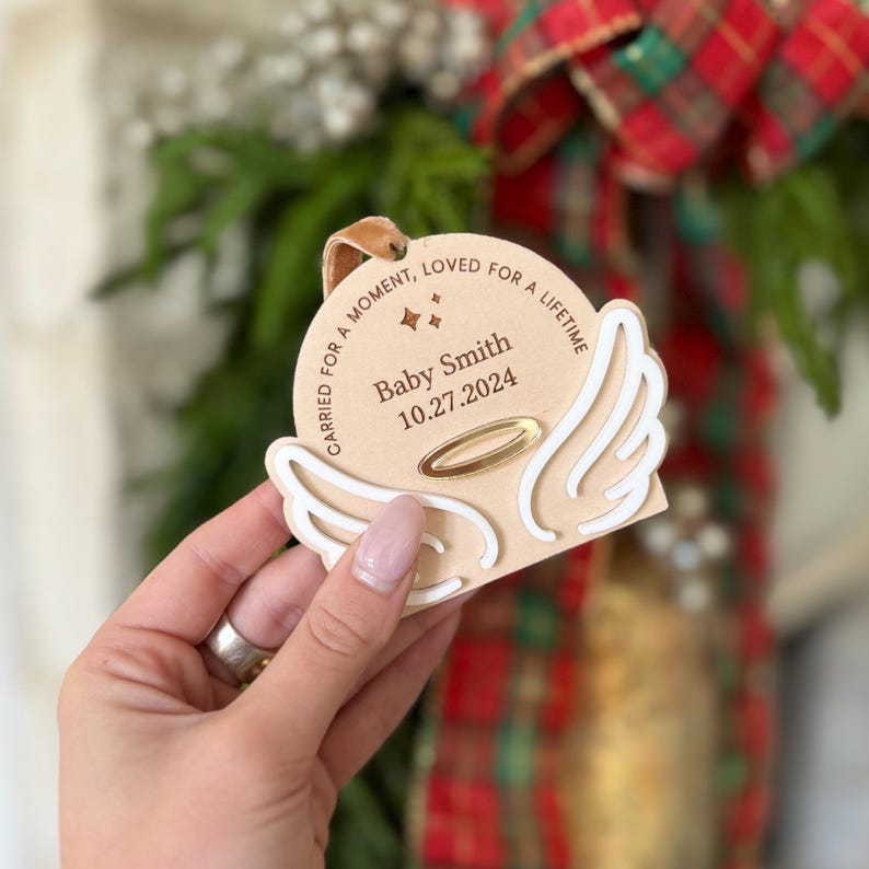 Wood or frosted acrylic baby memorial ornament.  Features matte white acrylic wings and a gold halo.  Personalize with baby's name and date.  Includes khaki velvet ribbon for hanging.