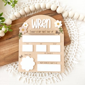 First/Last day of school sign with acrylic flowers and engraved butterflies. Features child's name in choice of acrylic color, and white areas to write milestones with a dry erase marker (not included).