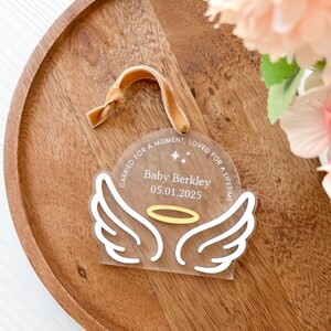 Wood or frosted acrylic baby memorial ornament.  Features matte white acrylic wings and a gold halo.  Personalize with baby's name and date.  Includes khaki velvet ribbon for hanging.