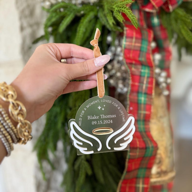 Wood or frosted acrylic baby memorial ornament.  Features matte white acrylic wings and a gold halo.  Personalize with baby's name and date.  Includes khaki velvet ribbon for hanging.