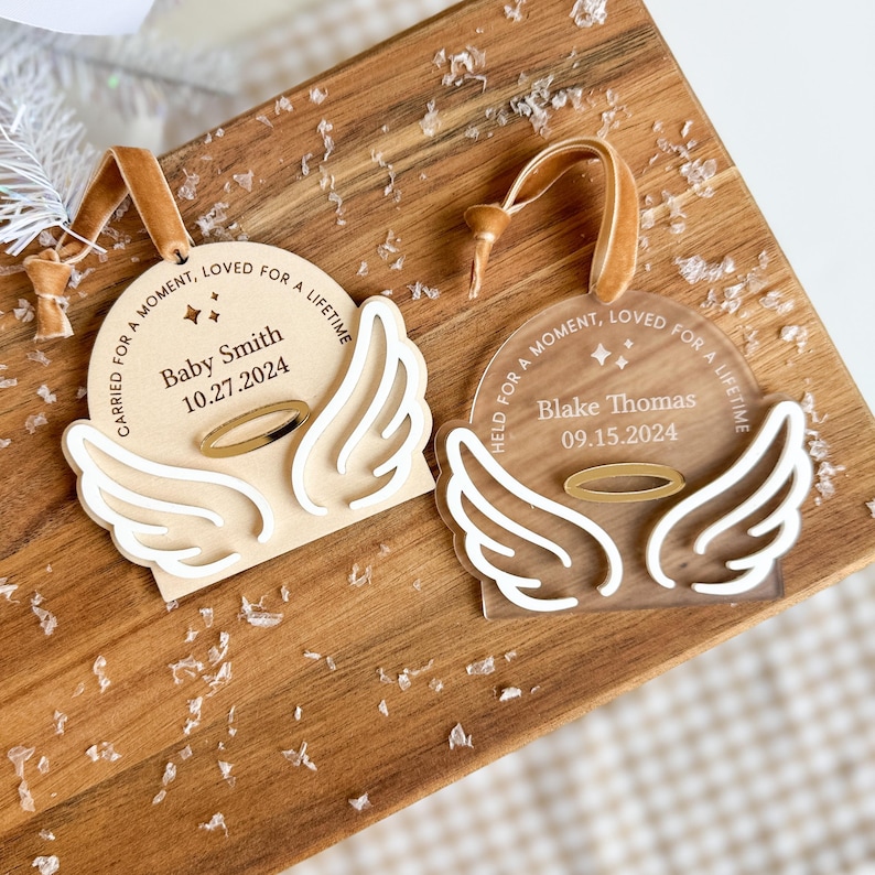 Wood or frosted acrylic baby memorial ornament.  Features matte white acrylic wings and a gold halo.  Personalize with baby's name and date.  Includes khaki velvet ribbon for hanging.