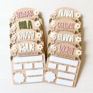 First/Last day of school sign with acrylic flowers and engraved butterflies. Features child's name in choice of acrylic color, and white areas to write milestones with a dry erase marker (not included).