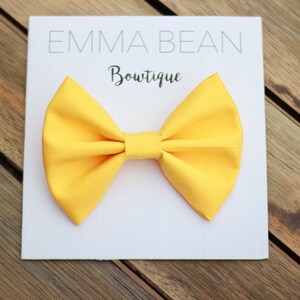 May include: A yellow bow tie on a white background with the text "Emma Bean Boutique".