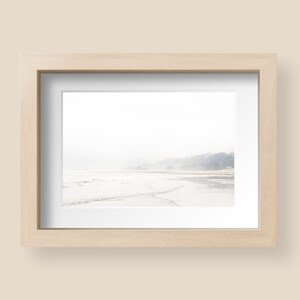 May include: A framed photograph of a beach scene with a misty, hazy background and a shoreline with waves crashing on the sand.