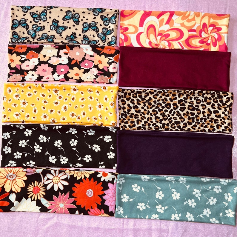 May include: Ten different fabric headbands with various patterns, including butterflies, flowers, and animal print. The headbands are all in different colors, including yellow, red, blue, green, and black.