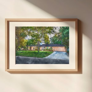 Könnte beinhalten: Ein gerahmtes Aquarellbild eines Einfamilienhauses in einem Vorort mit einem grünen Rasen und einer Auffahrt. Das Haus ist in einem hellen Pfirsichton mit weißen Verzierungen gestrichen. Die Bäume, die das Haus umgeben, sind grün und üppig.