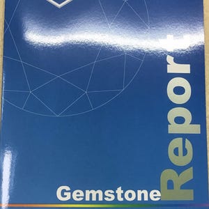 May include: A blue rectangular document titled Gemstone Report from the Nan Yang Gemological Institute Singapore. The cover features a white line drawing of a faceted gemstone and the NGI logo at the top left corner with a thin rainbow line.