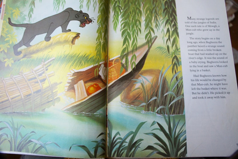 Puede incluir: Una p&aacute;gina ilustrada de un libro que representa a una pantera negra de pie sobre un tronco, mirando un peque&ntilde;o bote de madera con una cesta y un beb&eacute; dentro. El texto en la p&aacute;gina dice "Muchas leyendas extra&ntilde;as se cuentan sobre las junglas de la India. Una de esas historias es la de Mowgli, un hombre-ni&ntilde;o que creci&oacute; en la jungla."