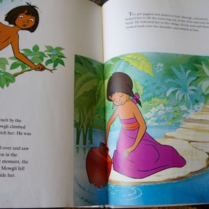 Puede incluir: Un joven, Mowgli, se sube a un &aacute;rbol para observar a una ni&ntilde;a arrodillada junto a un r&iacute;o. La ni&ntilde;a lleva un vestido morado y una diadema. Est&aacute; mirando su reflejo en el agua.