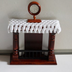 May include: A miniature wooden fireplace mantel with a white crocheted shelf cover and a small clock on top.