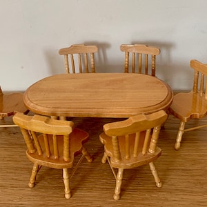 Könnte beinhalten: Ein Esstisch-Set aus Holz mit fünf Stühlen. Tisch und Stühle sind aus hellem braunem Holz gefertigt und haben ein schlichtes, klassisches Design.