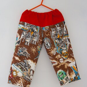 May include: Brown pants with a red waistband and a colorful print of robots and spaceships.