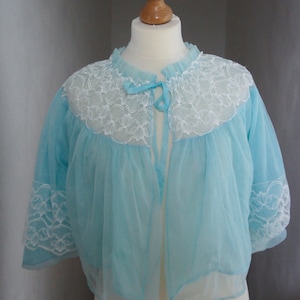 May include: A light blue sheer robe with white lace trim around the neckline and sleeves. The robe has a tie at the neckline.
