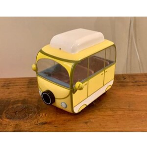 May include: A yellow toy bus with a white roof and a black window. The bus has a black exhaust pipe and a green stripe around the windows.