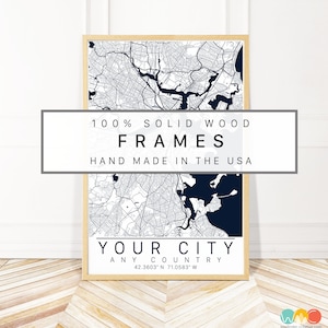May include: A framed map of a city with a navy blue and white color scheme. The frame is made of solid wood and the map is labeled "Your City" with the coordinates 42.3603 N 71.0583 W. The text "100% Solid Wood Frames Hand Made in the USA" is printed on a white rectangle at the top of the image.