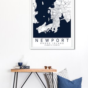 May include: A framed map of Newport, Rhode Island, with a white background and navy blue water. The map shows the city streets and coastline. The text "NEWPORT" and "RHODE ISLAND" are printed below the map, along with the coordinates "41.4900&deg; N 71.3138&deg; W".