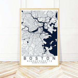May include: A framed map of Boston, Massachusetts, with a navy blue color scheme. The map shows the city's streets, waterways, and landmarks. The text "BOSTON MASSACHUSETTS 42.3603° N 71.0583° W" is printed below the map.