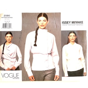 May include: A sewing pattern for a white blouse with a high collar and long sleeves. The pattern is by Vogue Patterns and is for sizes 14-18. The pattern is for a design by Issey Miyake.