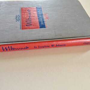 May include: A red hardcover book with the title "Wildwood" by Josephine W. Johnson and the publisher "Harper" printed on the spine.