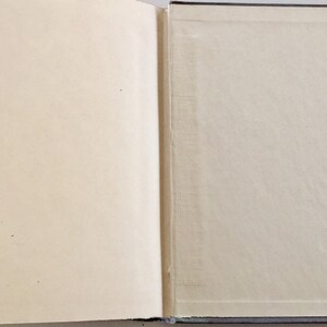 May include: A closed book with a blue cover and a white page visible. The book is lying flat on a surface.