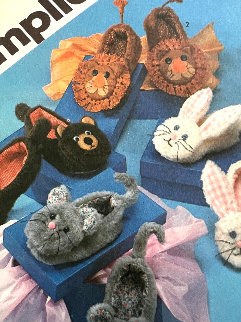 May include: A set of five animal-shaped slippers. The slippers are made of soft, plush fabric and feature embroidered faces. The animals include a lion, a bear, a bunny, and two cats.