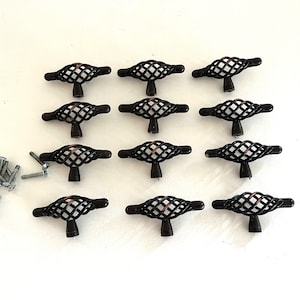 May include: Twelve black metal cabinet knobs with a decorative wire cage design and a copper finish. The knobs come with screws for installation.