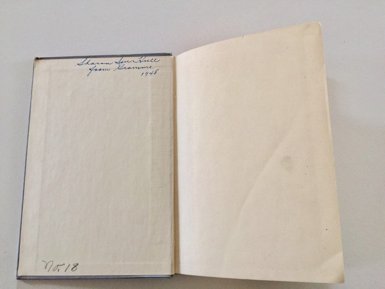 May include: A white book with blue writing on the cover. The writing says "Sharon Sue Hall from Grandma 1945" and "No. 18".