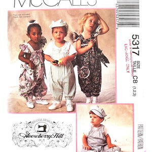 May include: McCall's sewing pattern for children's overalls and rompers. The pattern features multiple designs, including striped and floral options. The image shows children wearing the finished garments, with the "Hooseberry Hill" logo.