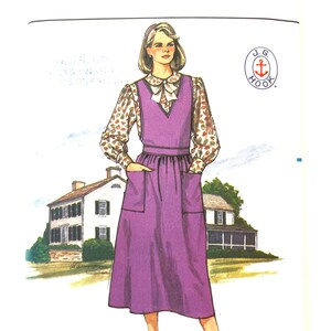 May include: A sewing pattern for a purple dress with a white blouse and a bow tie. The pattern is from Butterick and is for sizes 14-16-18. The pattern is for a dress with a V-neck and a skirt that falls to the knee. The pattern is also for a blouse with a Peter Pan collar and long sleeves.