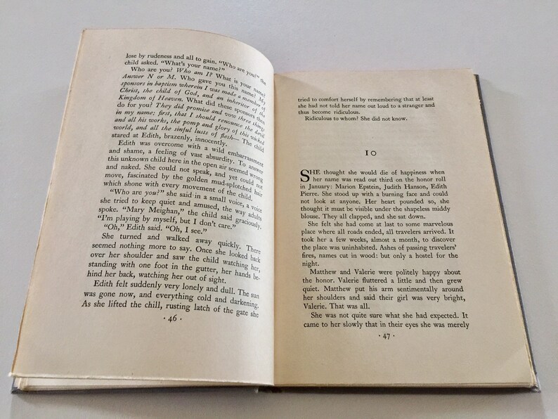 May include: A close-up of an open book with a white background. The text on the page reads, "She thought she would die of happiness when her name was read out third on the honor roll in January: Marion Epstein, Judith Hanson, Edith Pierre. She stood up with a burning face and could not look at anyone. Her heart pounded so, she thought it must be visible under the shapeless middy blouse. They all clapped, and she sat down."