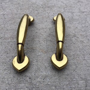 May include: Two gold-toned cabinet door pulls with a heart-shaped design at the bottom.