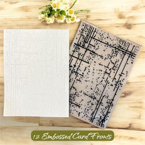 May include: Two white embossed card fronts with a grid pattern, next to a clear embossing folder with a black geometric design. The text "12 Embossed Card Fronts" is displayed on a green banner. A small bouquet of white and yellow flowers is in the background.