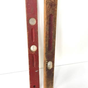 May include: Two vintage wooden levels, one red and one natural wood. Both have a glass bubble level and are approximately 18 inches long.