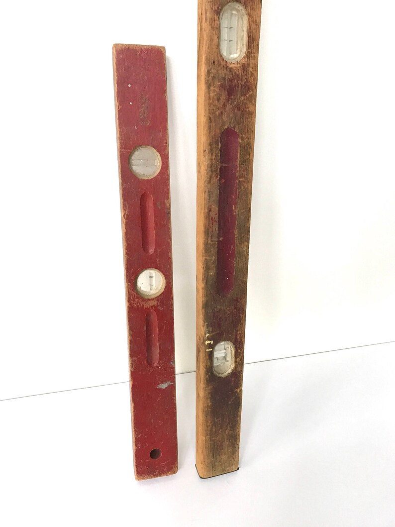 May include: Two vintage wooden levels, one red and one natural wood. Both have a glass bubble level and are approximately 18 inches long.