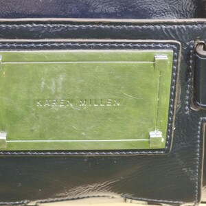 May include: A black leather handbag with a silver metal plate that reads "KAREN MILLEN".
