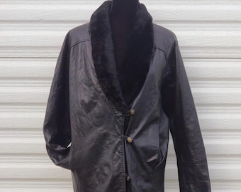 May include: A black leather coat with a faux fur collar. The coat has a button-up front and two pockets. The coat is displayed on a black mannequin.