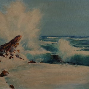 May include: Oil painting of a seascape featuring crashing waves against a rocky shore. The artwork depicts a dynamic scene with white foamy water, brown rocks, and a blue-green ocean under a pale blue sky. The painting is signed in the bottom right corner.