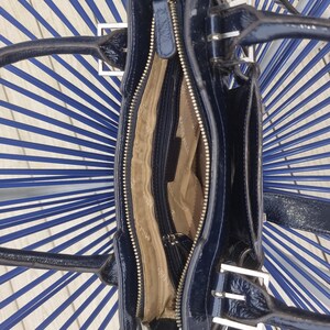 May include: A black patent leather handbag with silver hardware and a zipper closure. The bag has a top handle and a shoulder strap.