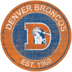 May include: A round, orange wooden sign with a blue circle in the center. The blue circle has a white "D" with a white bronco inside. The text "DENVER BRONCOS" is in a white circle around the blue circle. The text "EST. 1960" is at the bottom of the sign.