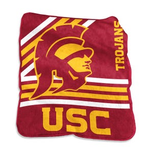 May include: A maroon fleece blanket featuring a large yellow Trojan helmet graphic, the text USC in bold yellow letters at the bottom, and the word TROJANS printed vertically in yellow on the right side, accented by white and yellow diagonal stripes.