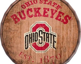May include: A round wooden sign with a distressed, vintage look. It features the Ohio State Buckeyes logo in red and grey with the words "Ohio State" and "Buckeyes" in red. The text "Est. 1870" is also included in red.