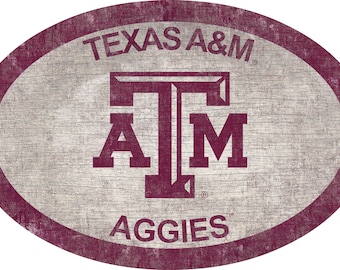 Könnte beinhalten: Ein ovales Schild in Maroon mit weißem Hintergrund und dem Text "TEXAS A&M" oben, einem Maroon "T" mit "A" und "M" darunter und dem Text "AGGIES" unten.
